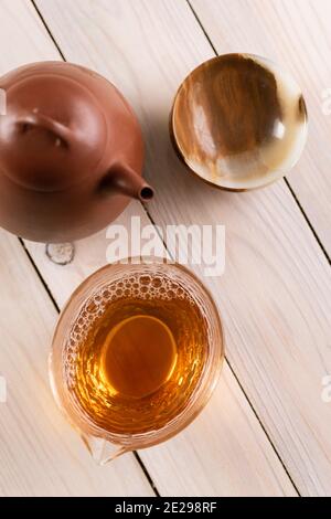 Bevanda sana flatlay. Tè vecchio shen puerh preparato in teiera di argilla e servito in chahai di vetro e una tazza di pietra onice su spazio copia tavolo di legno bianco Foto Stock