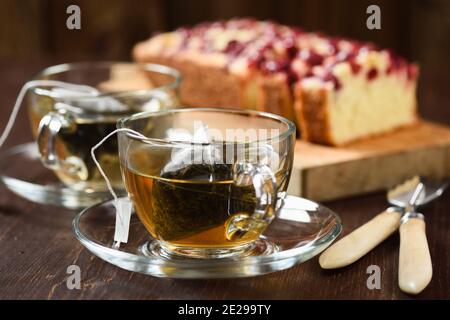 Bustine di tè piramidali prodotte in due tazze di vetro e bacche torta primo piano Foto Stock