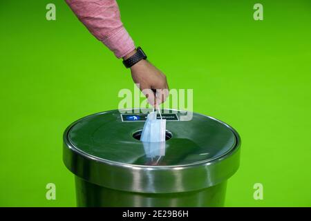 Un uomo toglie la maschera medica protettiva e lo scarico in cestino Foto Stock