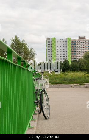 POZNAN, POLONIA - 12 agosto 2017: Bicicletta appoggiata contro una barriera verde di metallo su una strada con edificio in lontananza Foto Stock