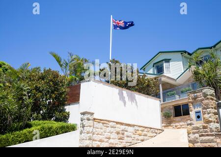 Casa costiera di Sydney a Avalon Beach con giardino lussureggiante E bandiera australiana che vola su flagpole, Sydney, Australia Foto Stock