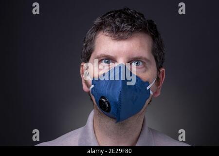 Maschio caucasico con maschera facciale del respiratore blu scuro N95. Foto Stock