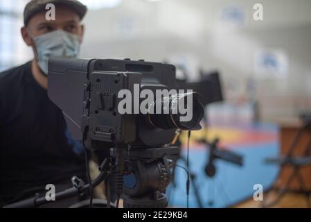 L'operatore mascherato spara un flusso sul Internet che trasmette a. un evento sportivo Foto Stock