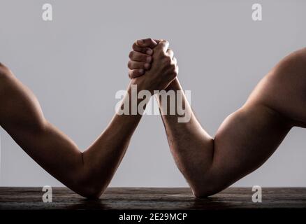 Braccio wrestling. Braccio uomo molto muscled che lotta un uomo debole puny. Armi che lottano con la mano sottile e un grande braccio forte in studio. Due mani dell'uomo si sono aggrappate al braccio Foto Stock