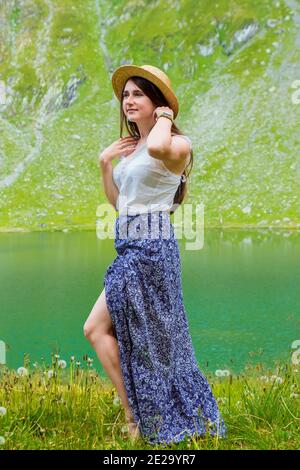 Una bella donna in un vestito e cappello si trova vicino Del Lago Balea Foto Stock