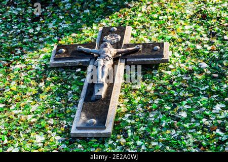 Crocifisso su pietra tombale ricoperto di luccicante lastre di vetro. Tipica tradizione commemorativa delle sepolture nei cimiteri di Cotentin, Normandia, Francia. Foto Stock