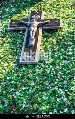 Crocifisso su pietra tombale ricoperto di luccicante lastre di vetro. Tipica tradizione commemorativa delle sepolture nei cimiteri di Cotentin, Normandia, Francia. Foto Stock