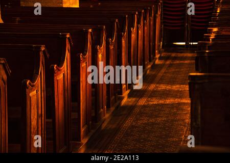 Mistero del tempio. Panchine di legno in chiesa vuota scura. La luce del sole illumina le torce e il pavimento di passaggio con un bel motivo. Background religioso. Foto Stock