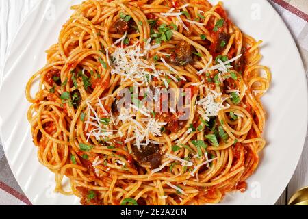 pasta spaghetti alla norma su un piatto bianco su un tavolo di legno testurizzato bianco, cucina italiana, vista orizzontale dall'alto, piatto, macro Foto Stock