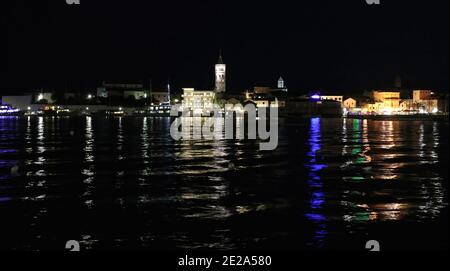 Croazia, regione del Quarnero, isola di Rab, vista panoramica del porto di Rab di notte con luci che si riflettono sull'acqua Foto Stock
