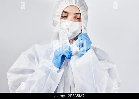 Un medico stanco e frustrato che si sottragga all'usura protettiva. Covid combatte la fatica. L'operatore sanitario toglie i dispositivi di protezione individuale Foto Stock