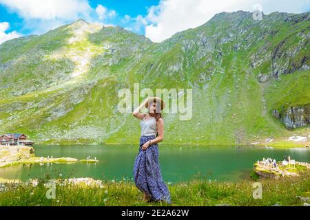 Una bella donna in un vestito e cappello si trova vicino Del Lago Balea Foto Stock