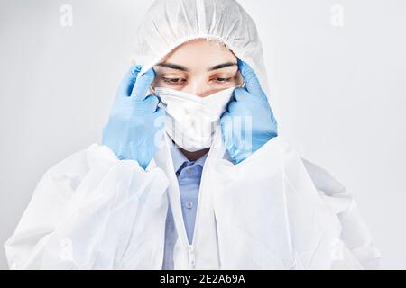 Un medico stanco e frustrato che si sottragga all'usura protettiva. Covid combatte la fatica. L'operatore sanitario toglie i dispositivi di protezione individuale Foto Stock