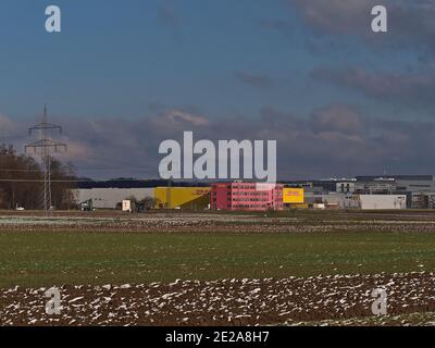 Centro logistico della società di trasporti DHL Global Forwarding, parte del Gruppo Deutsche Post DHL, con logo commerciale e campi agricoli. Foto Stock