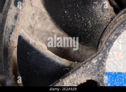 Parte di una ventola della CPU sporca. Profondità di campo poco profonda, messa a fuoco sulla parte superiore della lama. La sporcizia sotto il dissipatore di calore intasa completamente, ma non è in profondità di campo. Foto Stock