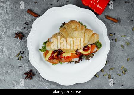 Delizioso croissant al prosciutto e formaggio cheddar con insalata Foto Stock