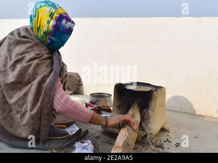 Rurale indiano femmina preparare chapati in un modo tradizionale un forno a legna Foto Stock