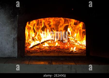 Fuoco e fiamme si vedono all'interno di un vecchio forno rurale a legna o forno. Foto Stock