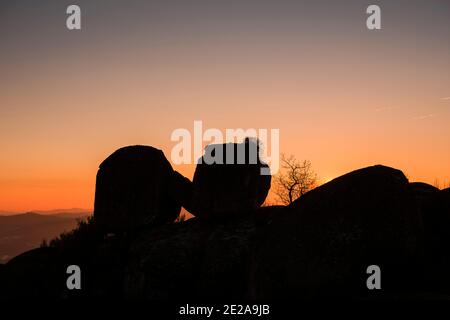 Due grandi rocce di pietra che si appoggiano l'una contro l'altra in retroilluminazione al tramonto Foto Stock