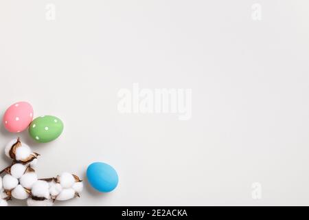 Buona Pasqua. Uova multicolore e un ramo di cotone su sfondo grigio. Biglietto d'auguri Flat Lay con spazio per la copia. Foto Stock