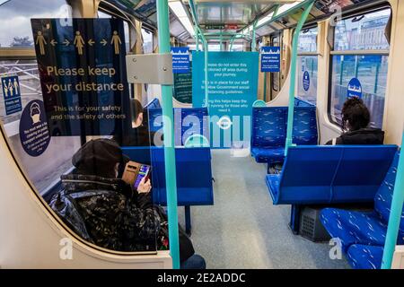 Londra, Regno Unito. 12 gennaio 2021. La DLR è ancora abbastanza occupata, in quanto si avvicina al centro di vaccinazione di massa di Excel. Nessuna delle persone ci sta dirigendo, tuttavia, e sono fuori nonostante la nuova nazionale Lockdown, soggiorno a casa, istruzioni. La maggior parte dei viaggiatori indossano maschere in quanto sono già obbligatori e ci sono segnali di avvertimento ovunque. Credit: Guy Bell/Alamy Live News Foto Stock