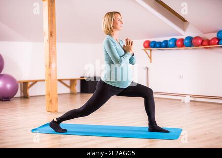 Donna incinta ama praticare yoga, Virabhadrasana-Warrior posa Foto Stock