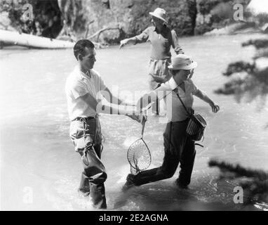 MYRNA LOY e membri del Film Crew sul set location candid Durante le riprese di Fishing Sequence in LIBELED LADY 1936 regista JACK CONWAY Metro Goldwyn Mayer Foto Stock