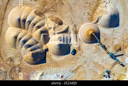 Foto aerea dei cumuli di sabbia che vengono spostati con un convettore e un caricatore frontale. La foto è stata scattata con un drone Mavic 2 Pro. Foto Stock