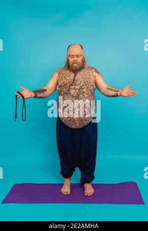 Hipster uomo con tatuaggi facendo yoga e meditazione esercizi in la mattina Foto Stock