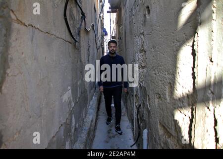 (210113) -- GAZA, 13 gennaio 2021 (Xinhua) -- UN uomo cammina in un vicolo nel campo profughi di al-Shati nella città di Gaza, 11 gennaio 2021. Il 24 agosto 2020, le autorità di Gaza, gestite da Hamas, hanno annunciato i primi quattro casi di COVID-19 e hanno imposto una serie di misure restrittive per frenare la diffusione del virus. Da allora, tutte le chiese, le moschee, le scuole, i mercati e le istituzioni private sono stati chiusi e sono state vietate le riunioni pubbliche. PER ANDARE CON "Feature: Gli studenti palestinesi rifugiati sperano di una piena istruzione nell'era post-pandemica" (Foto di Rizek Abdeljawad/Xinhua) Foto Stock