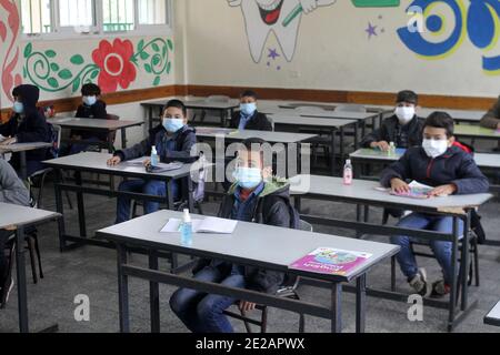 (210113) -- GAZA, 13 gennaio 2021 (Xinhua) -- studenti palestinesi che indossano maschere per il viso frequentano una classe in una scuola dopo la sua riapertura come la COVID-19 misure di restrizione facilità nella città di Gaza, 13 gennaio 2021. (Foto di Rizek Abdeljawad/Xinhua) Foto Stock