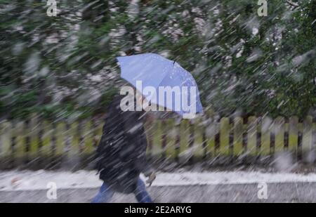 Amburgo, Germania. 13 gennaio 2021. Un uomo si protegge dai fiocchi di neve con un ombrello. Credit: Marco Brandt/dpa/Alamy Live News Foto Stock