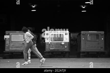 Due persone che corrono per strada. Macchine postali. USA, Philadelphia, 1976 Foto Stock