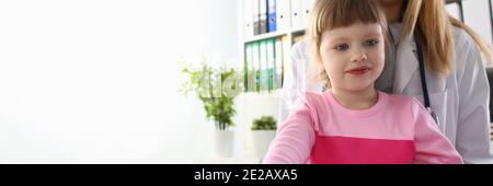 Sorridente bambina che visita madre al lavoro in clinica Foto Stock