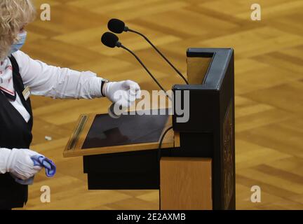 Amburgo, Germania. 13 gennaio 2021. Un dipendente disinfetta il leggio durante la sessione del Parlamento di Amburgo nel Municipio di Amburgo. Tra gli argomenti trattati figurano la nuova ordinanza sul contenimento della corona, il bilancio 2021/2022 e la digitalizzazione nelle scuole. Credit: Ulrich Perrey/dpa/Alamy Live News Foto Stock