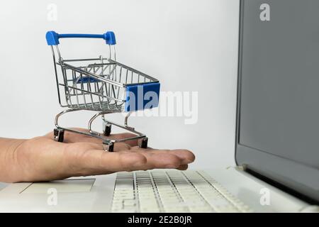 Shopping su Internet. Computer portatile con piccolo carrello sul tavolo,  primo piano Foto stock - Alamy