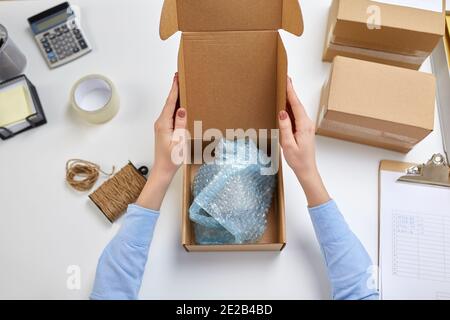 consegna la tazza di imballaggio alla scatola del pacco presso l'ufficio postale Foto Stock