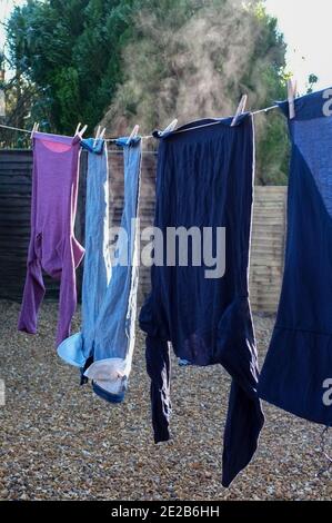 I vestiti appena lavati si stagliano al sole in una giornata molto fredda. Foto Stock
