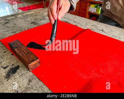 Un calligrafo sta creando e scrivendo i couplets del festival di primavera, il festival cinese di primavera di Capodanno Foto Stock