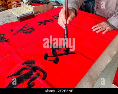Un calligrafo sta creando e scrivendo i couplets del festival di primavera, il festival cinese di primavera di Capodanno Foto Stock