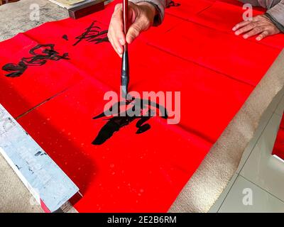 Un calligrafo sta creando e scrivendo i couplets del festival di primavera, il festival cinese di primavera di Capodanno Foto Stock