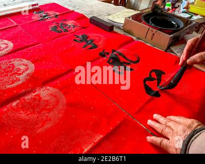 Un calligrafo sta creando e scrivendo i couplets del festival di primavera, il festival cinese di primavera di Capodanno Foto Stock