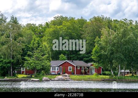 Vista su una cabina rossa per le vacanze vicino a un lago nell'arcipelago di Stoccolma, Svezia Foto Stock