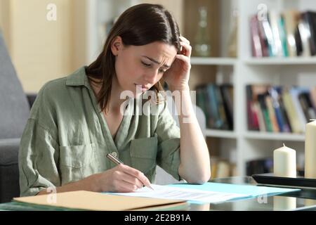 Donna triste pronta a firmare un contratto che si lamenta a casa Foto Stock