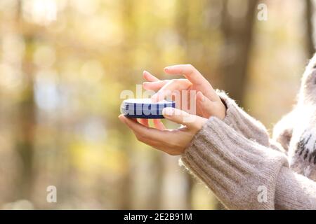 Primo piano delle mani della donna che tengono una bottiglia di crema idratante inverno in un parco Foto Stock