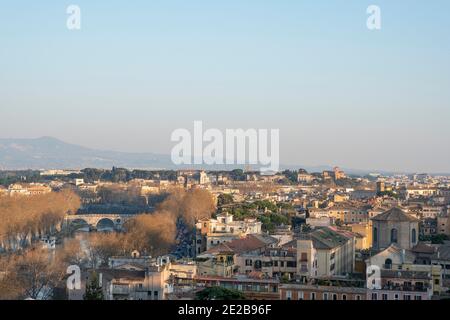 Vista sui tetti di Trastevere, Roma, Italia, fino al Tevere e alle chiese sul colle Aventino in mezzo, e le colline oltre la città. Foto Stock