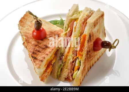 toast alla griglia con lattuga al prosciutto e pomodori, tagliati a metà isolati su bianco Foto Stock