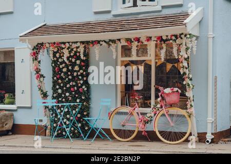 Cheddar, Regno Unito - 26 luglio 2020: Bici rosa parcheggiata da pastello colorata la stanza della squadra di Lion Rock a Cheddar, un villaggio famoso per la sua Gola ed è il birthpl Foto Stock