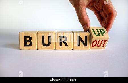 Bruciare, non bruciare. La mano maschio capovolge un cubo di legno e cambia le parole 'burnout' in 'burn up' o viceversa. Splendido sfondo bianco, spazio per la copia. BU Foto Stock