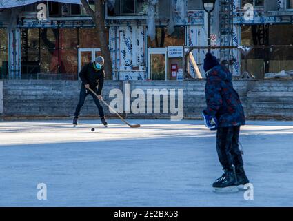 9 gennaio 2021 - Montréal, QC, Canada: Uomo che indossa una maschera mentre gioca a hockey con un bambino durante COVID Coronavirus Pandemic, Rosemont borough Foto Stock